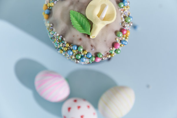 三个白色复活节彩蛋的特写，心形和波浪的图案，还有一个花装饰的蛋糕。东正教复活节在蓝色背景俯视图图片下载