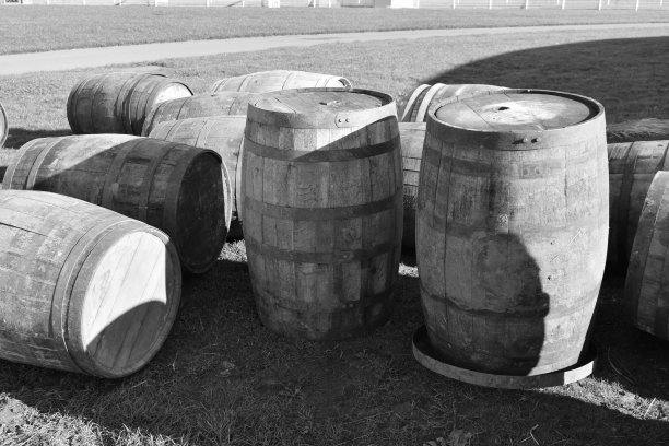 这是一张黑白照片，照片上老式的木制啤酒桶站在外面的草地上图片下载