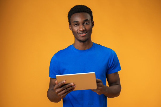 微笑的非洲人在黄色背景上使用数码平板电脑图片下载
