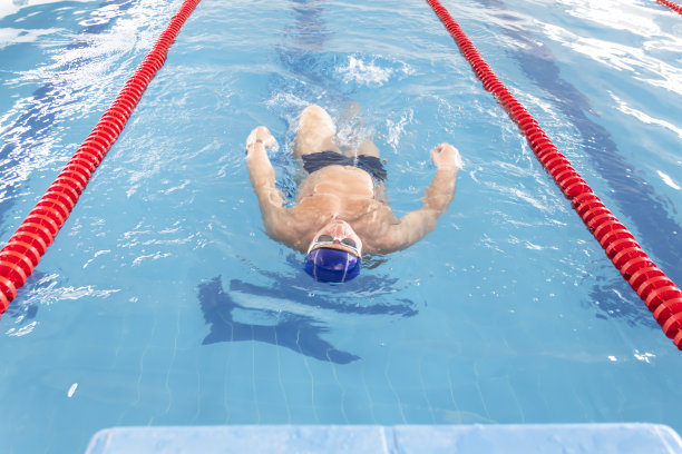 一名男运动员在蓝色海水中的游泳池运动中心游泳。图片下载