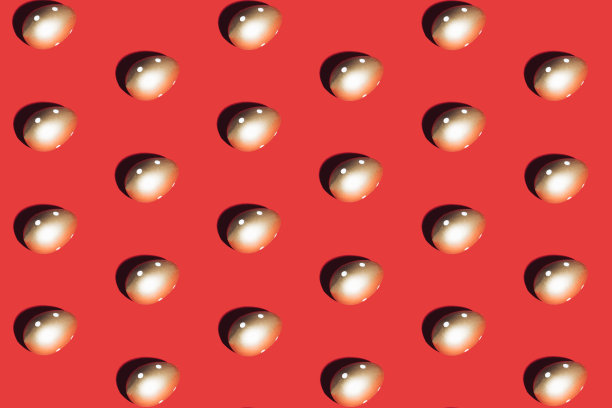 红色背景上的金蛋图案。最小的复活节或食物概念。图片下载