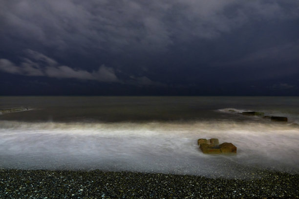 晚上的照片。破旧的码头和满月的大海。夜间海上冲浪。图片下载