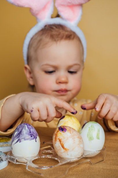 一个孩子在黄色的背景上画复活节彩蛋图片下载