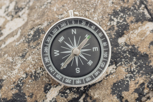 指南针在美丽的彩色岩石上，上面有沙滩的沙子图片下载