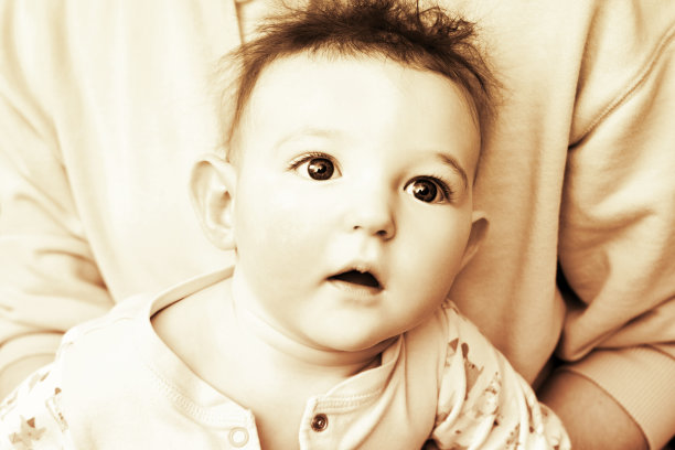 惊讶的婴儿，蓝色的大眼睛，蓬乱的头发，棕褐色。一个头发凌乱的受惊的孩子的肖像，黑白相间图片下载