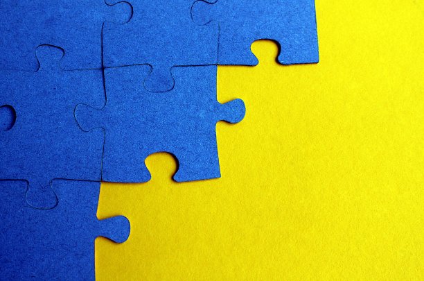 蓝色的拼图被放置在平坦的黄色表面上。图片下载