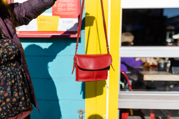 在色彩斑斓的建筑外，手拿红色手提包的女人图片下载