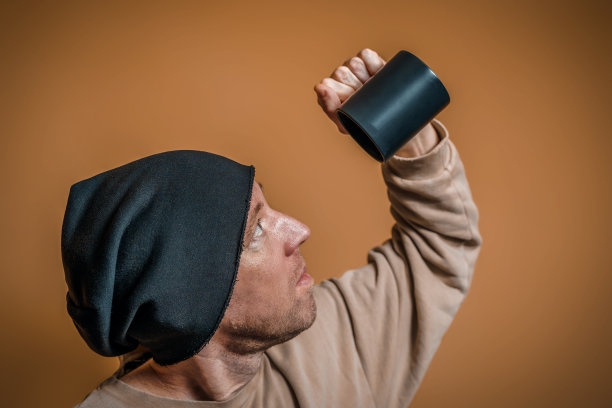 一个戴着黑色帽子的年轻人的肖像。一个男人惊讶地看着一个黑色的杯子图片下载