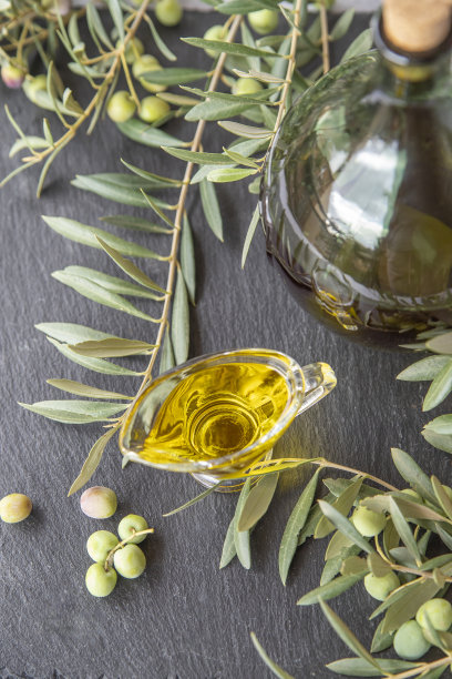 绿色橄榄与橄榄油在黑暗的背景图片下载