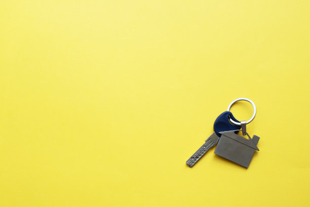 钥匙与钥匙链的形式，在明亮的黄色背景上的房子。铭文。图片下载