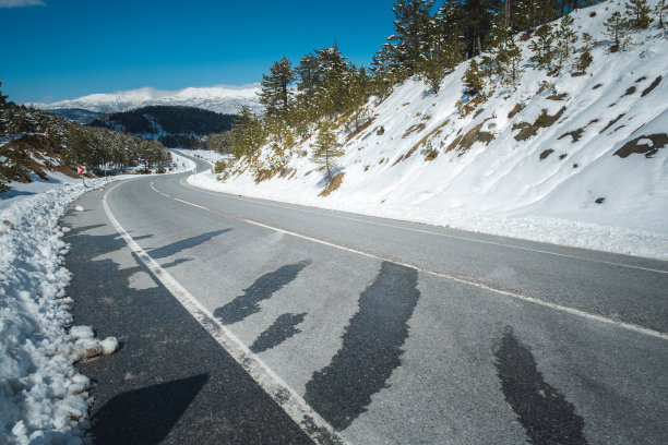 弯弯曲曲的柏油路在白雪皑皑的自然山峦间，有霜冻的危险图片下载