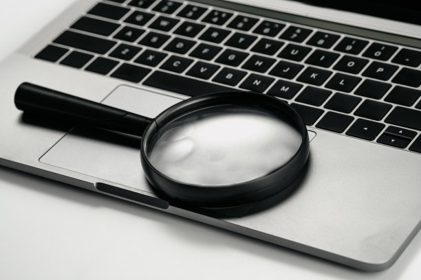 电脑和放大镜在白色背景板上图片下载