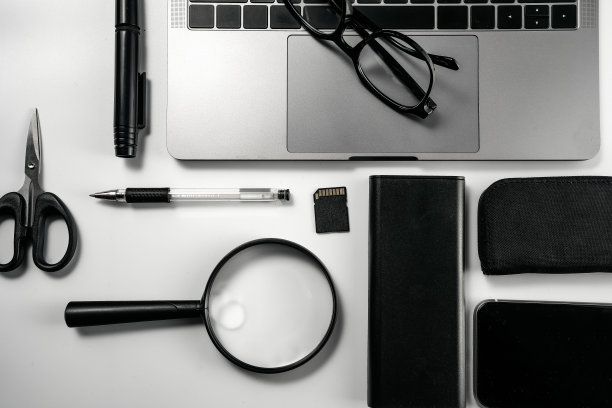 电脑，眼镜，放大镜，剪刀，卡片，夹子和笔在白色背景板上图片下载