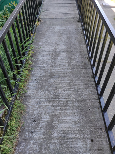垂直的照片，狭窄的水泥灰色的道路或桥梁或道路与黑色的栏杆或铁质金属侧边条或栏杆图片下载