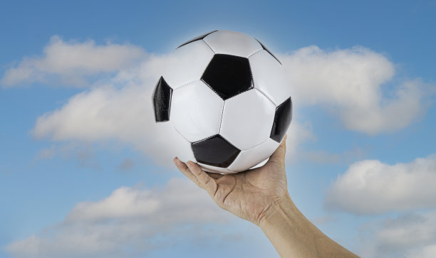 足球的特写镜头在男子手上与多云和蓝色的天空背景为欢呼的形象图片下载