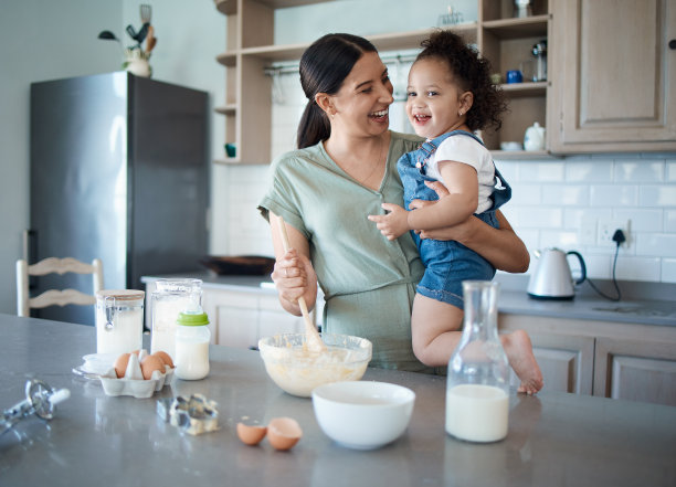 这张照片拍摄的是一位年轻的妈妈和她蹒跚学步的孩子在家里烤面包图片下载