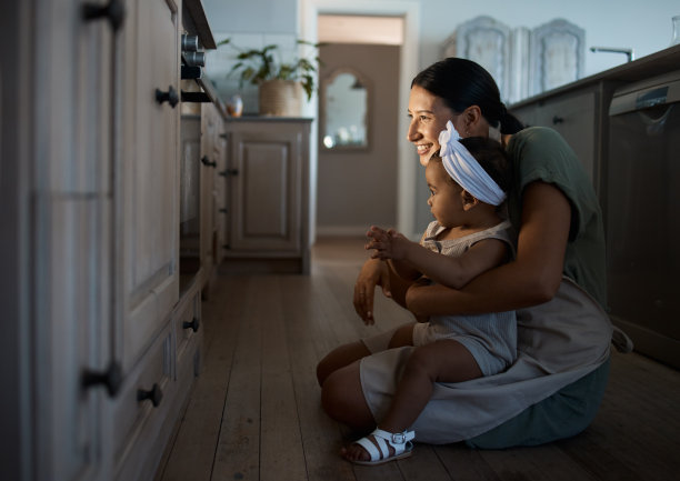 这张照片拍摄的是一位年轻的妈妈和她蹒跚学步的孩子在家里烤面包图片下载