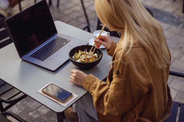 一名妇女在午休时间用筷子在外面吃饭图片下载