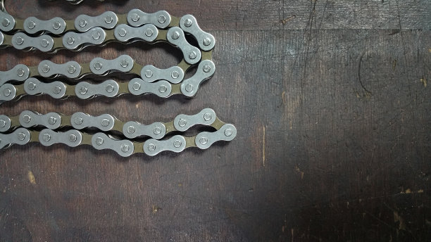 照片自行车零件-自行车链-关闭在一个黑暗的木头背景图片下载