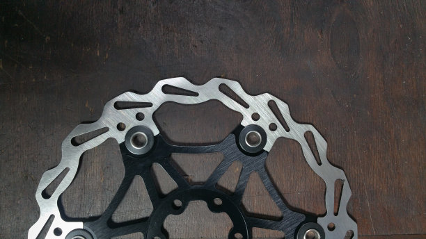 照片自行车零件-自行车制动盘-近在一个黑暗的木头背景图片下载