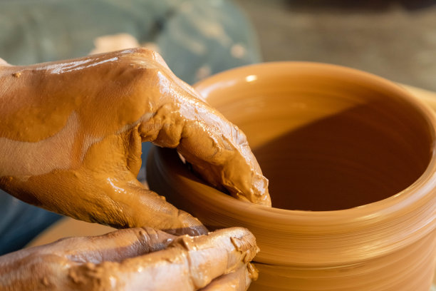 陶工的双手在陶轮上制作陶器。天然材料、手工制作和创意的概念。图片下载