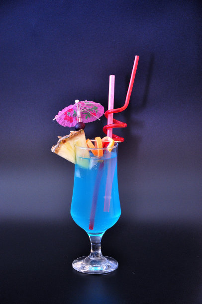 清爽的鸡尾酒蓝色泻湖与一片菠萝和管在一个高的杯子在黑色的背景。图片下载