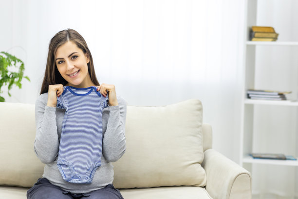 孕妇抱着小孩小衣服的照片。图片下载