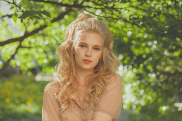 可爱的金发女人在绿色的叶子背景图片下载