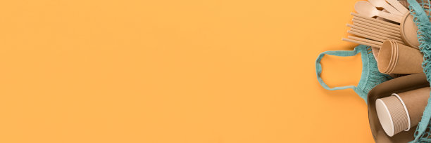 横幅与环保的纸器皿-牛皮纸食品杯和容器在棉网袋橙色背景与复制空间。街头小吃带走纸餐具-杯子，盘子，吸管，木制餐具。模型图片下载