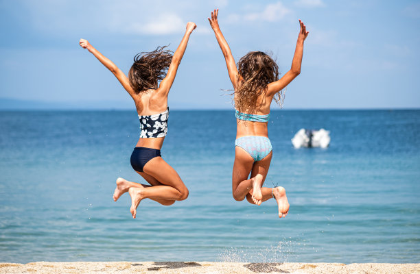 两个女孩在海滩上跳跃图片下载