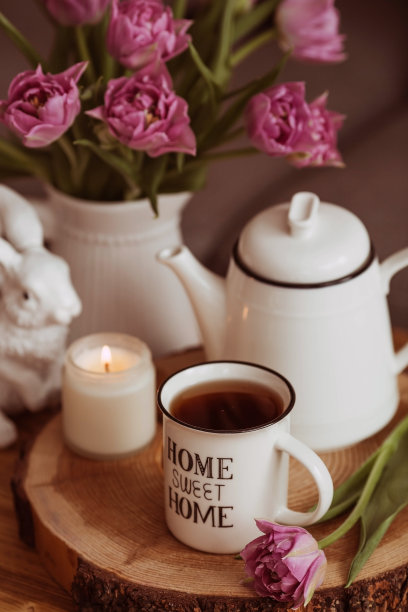 静物。客厅室内的咖啡桌上摆放着花瓶、郁金香、茶壶、兔子、蜡烛和一杯茶。舒适的弹簧的概念。图片下载