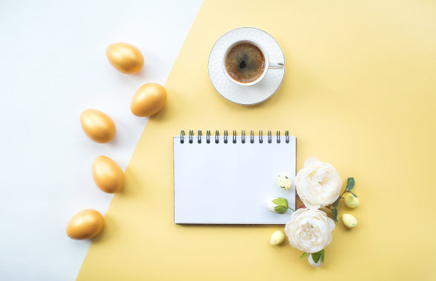 金色的复活节彩蛋，咖啡杯，精致的花和笔记本与地方的文本在黄色的背景上。时髦的公寓。最小的概念。图片下载