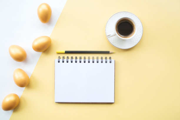 金色的复活节彩蛋，咖啡杯和笔记本与地方的文本在黄色的背景上。时髦的公寓。最小的概念。图片下载