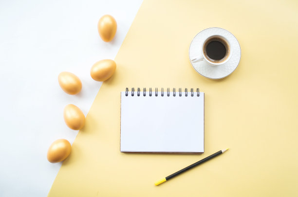 金色的复活节彩蛋，咖啡杯和笔记本与地方的文本在黄色的背景上。时髦的公寓。最小的概念。图片下载