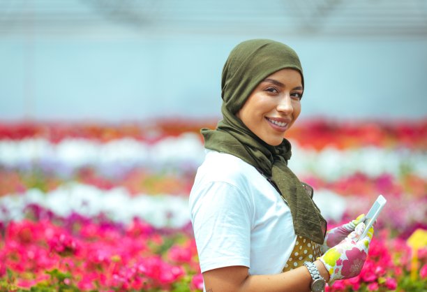 微笑的穆斯林妇女在彩色花圃上打字，自由的空间图片下载