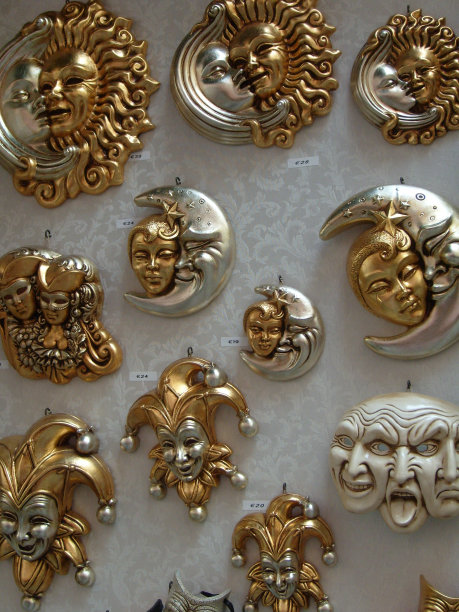 商店橱窗里出售的威尼斯节日用的金银面具。价格以欧元计算。纪念面具描绘人的脸，太阳和月亮的脸，剧场里的萨提斯，小丑和小丑的脸图片下载