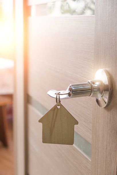 钥匙和钥匙扣在房间的门锁上。明亮的阳光下。图片下载