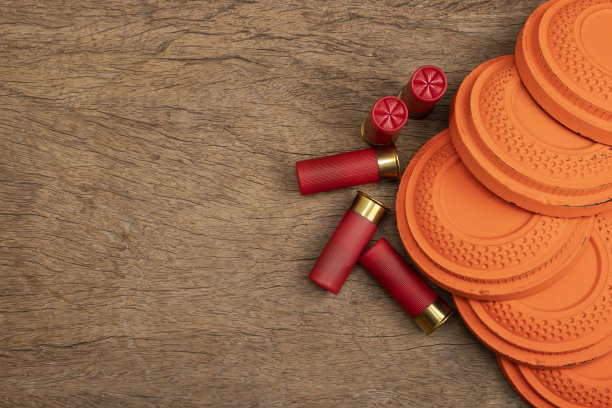 飞行粘土鸽子目标与射击枪子弹炮弹在木制背景，射击游戏图片下载