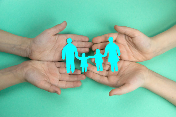 孩子们的手握着一个家庭的剪纸剪影，背景是绿色的。友好健康的大家庭孩子们的家庭梦想，家庭暴力。友好的家庭。图片下载