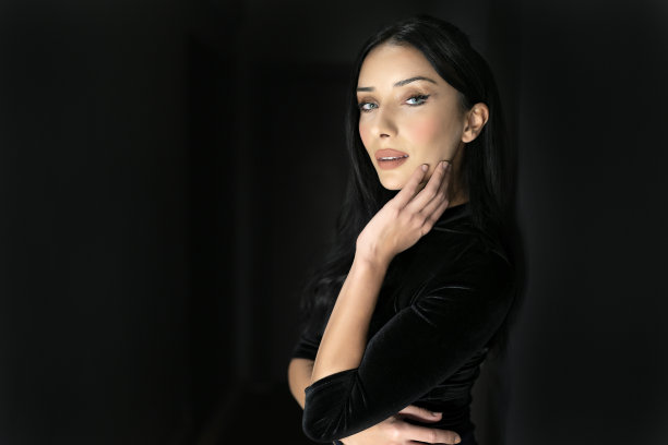 迷人的时尚女孩在灰色背景上优雅的黑色上衣的侧面肖像。图片下载