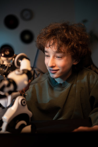 男孩痴迷于电子手表机器人，玩玩具。晚上的房间，被蓝色的辉光照亮图片下载