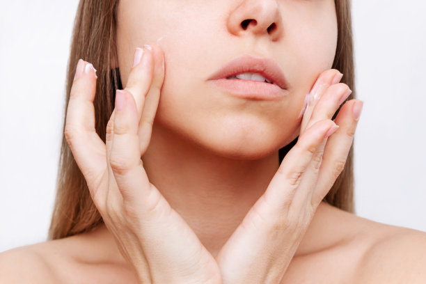年轻迷人的白种人金发女人触摸脸与她的手应用保湿霜图片下载