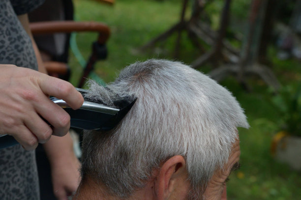 一个理发师理发时头发花白的人的特写图片下载
