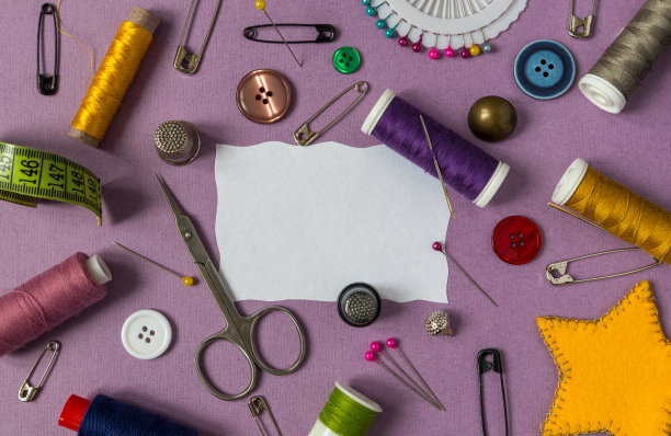 带缝纫工具的框架。缝纫线，针，别针，剪刀，纽扣在紫色的背景上有一个地方的文字。前视图,图片下载