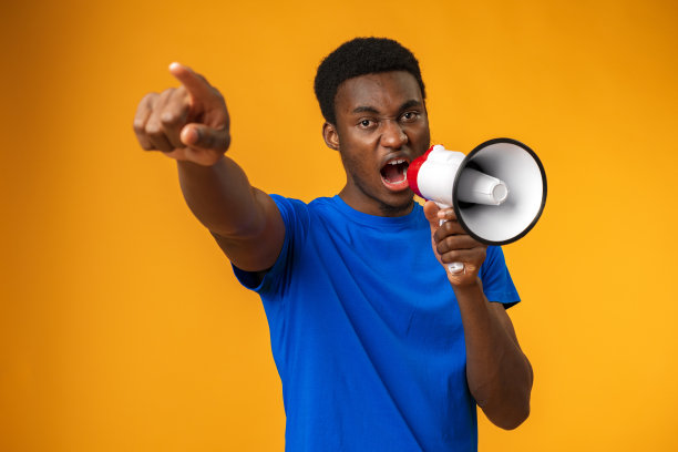 一个年轻的黑人在黄色背景下用扩音器大喊图片下载