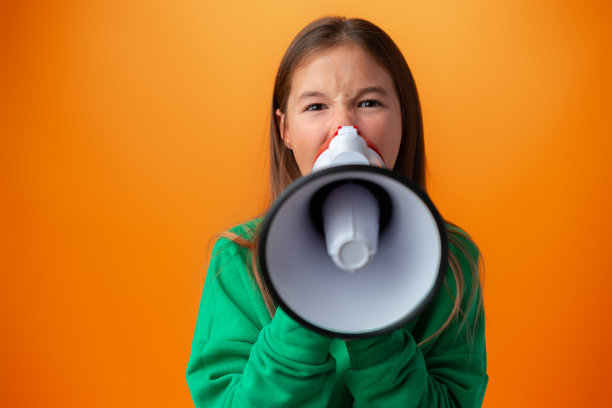在橙色背景下用扩音器做通知的少女图片下载