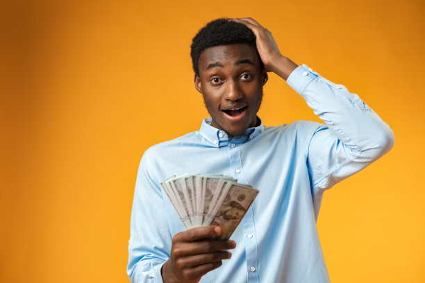 一个激动的黑人在黄色画室里拿着一叠美元图片下载