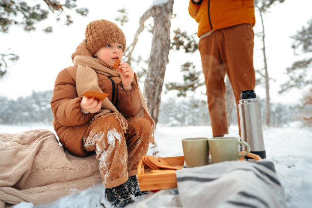 一个小男孩在冬天的森林里野餐图片下载