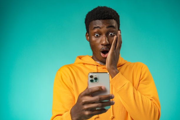 激动的黑人在演播室里用手机读好消息图片下载