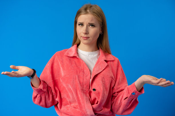 一个美丽的困惑的年轻女孩的肖像在蓝色的背景图片下载